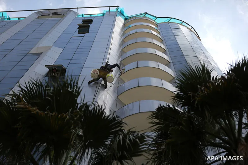 A Palestinian window cleaner hangs from ropes as he cleans windows of Al-zafer tower in Gaza City, in March 15, 2017. Photo by Yasser Qudih