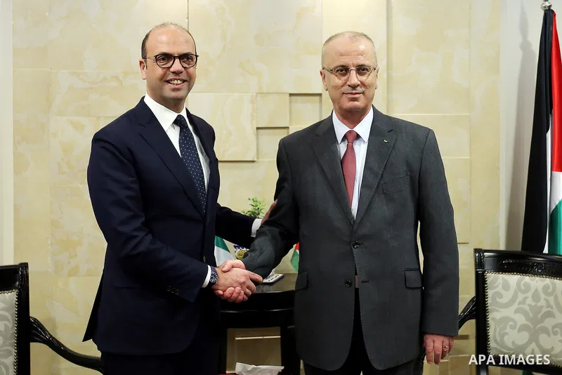 Palestinian Prime Minister Rami Hamdallah shakes hand with Italian Foreign Minister Angelino Alfano during a meeting in the West Bank city of Ramallah on March 15, 2017. Photo by Prime Minister Office
