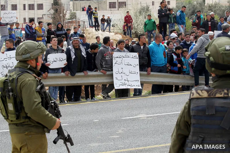 Palestinian protesters hold placards during a protest calling for the reopening of a closed street in the West Bank city of Hebron on March 17, 2017. Photo by Wisam Hashlamoun