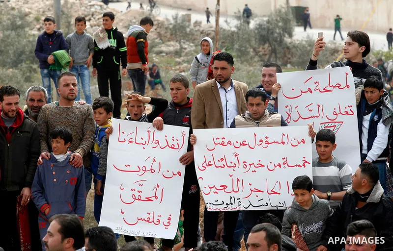 Palestinian protesters hold placards during a protest calling for the reopening of a closed street in the West Bank city of Hebron on March 17, 2017. Photo by Wisam Hashlamoun