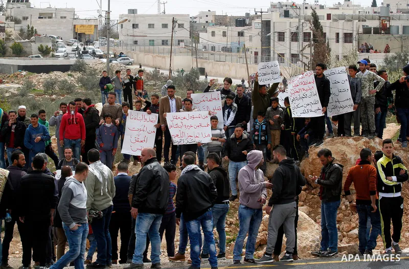 Palestinian protesters hold placards during a protest calling for the reopening of a closed street in the West Bank city of Hebron on March 17, 2017. Photo by Wisam Hashlamoun