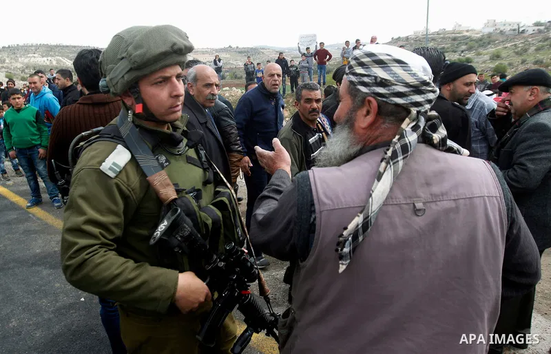 An Israeli soldier argues with a Palestinian protester during a protest calling for the reopening of a closed street in the West Bank city of Hebron on March 17, 2017. Photo by Wisam Hashlamoun