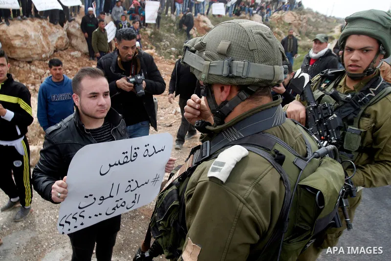 Palestinian protesters hold placards during a protest calling for the reopening of a closed street in the West Bank city of Hebron on March 17, 2017. Photo by Wisam Hashlamoun