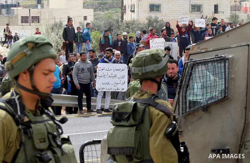 Palestinian protesters hold placards during a protest calling for the reopening of a closed street in the West Bank city of Hebron on March 17, 2017. Photo by Wisam Hashlamoun