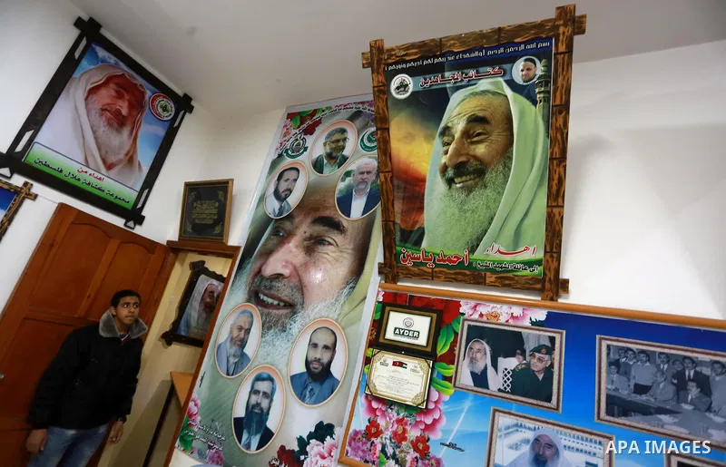 A Palestinian youth walks past pictures for late Hamas leader Sheikh Ahmed Yassin who was killed in an Israeli attack, in his house marking the thirteenth anniversary of his death, in Gaza City, March 21, 2017. Photo by...
