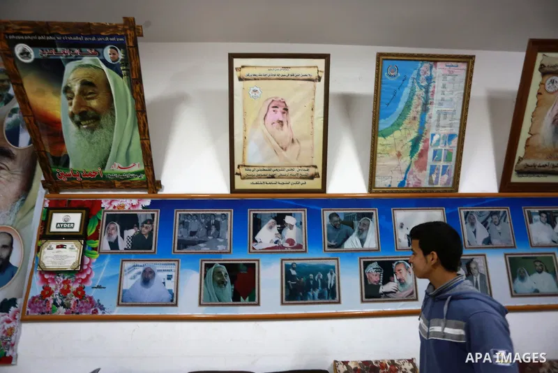 A Palestinian youth walks past pictures for late Hamas leader Sheikh Ahmed Yassin who was killed in an Israeli attack, in his house marking the thirteenth anniversary of his death, in Gaza City, March 21, 2017. Photo by...