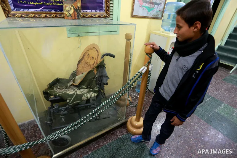 A Palestinian boy stands next to wheel chair of late Hamas leader Sheikh Ahmed Yassin who was killed in an Israeli attack, in his house marking the thirteenth anniversary of the death, in Gaza City, March 21, 2017. Photo...