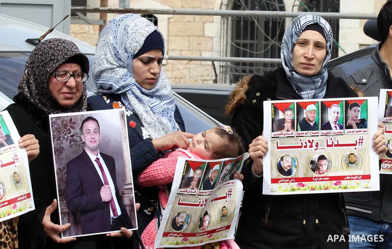 Palestinians hold photos of their relatives who were allegedly involved in attacks and consequently killed by Israeli forces, during a protest to demand the return of their bodies in the West Bank of Bethlehem on March 2...