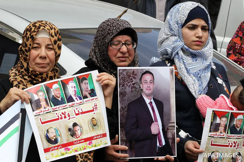 Palestinians hold photos of their relatives who were allegedly involved in attacks and consequently killed by Israeli forces, during a protest to demand the return of their bodies in the West Bank of Bethlehem on March 2...