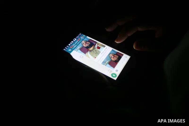 A Palestinian man watches a photo of the body of Hamas official, Mazen Faqha who was shot dead by gunmen in the Gaza Strip at his phone in Gaza City on March 24, 2017. Faqha was released along with more than 1,000 other...