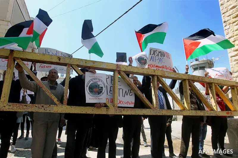 Palestinian demonstrators hold national flags and placards during a protest against Jewish settlements in the West Bank city of Hebron March 26, 2017. Photo by Wisam Hashlamoun