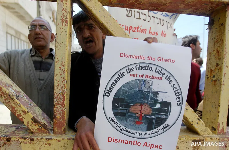 A Palestinian demonstrator holds a placard during a protest against Jewish settlements in the West Bank city of Hebron March 26, 2017. Photo by Wisam Hashlamoun