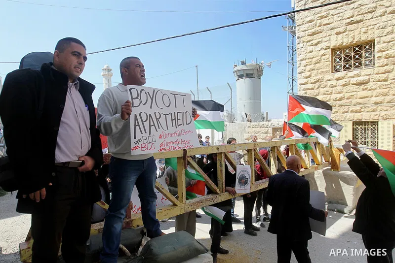 Palestinian demonstrators hold national flags and placards during a protest against Jewish settlements in the West Bank city of Hebron March 26, 2017. Photo by Wisam Hashlamoun