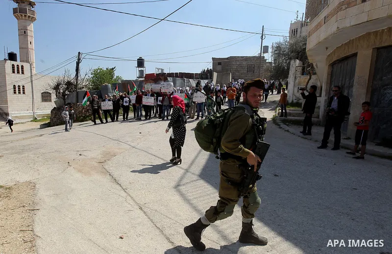 Palestinian demonstrators hold national flags and placards during a protest against Jewish settlements in the West Bank city of Hebron March 26, 2017. Photo by Wisam Hashlamoun