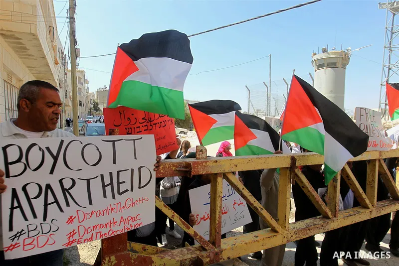 Palestinian demonstrators hold national flags and placards during a protest against Jewish settlements in the West Bank city of Hebron March 26, 2017. Photo by Wisam Hashlamoun