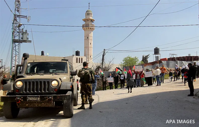 Palestinian demonstrators hold national flags and placards during a protest against Jewish settlements in the West Bank city of Hebron March 26, 2017. Photo by Wisam Hashlamoun
