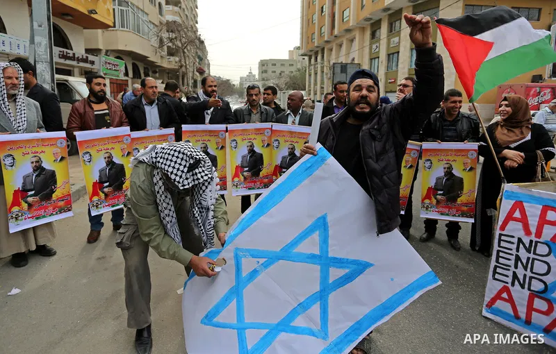 Palestinians burn an Israeli flag during a protest denouncing an assassination of Hamas official, Mazen Faqha who was freed by Israel in a 2011 prisoner swap after he was shot dead by unknown gunmen, in front of Red cros...