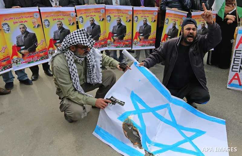 Palestinians burn an Israeli flag during a protest denouncing an assassination of Hamas official, Mazen Faqha who was freed by Israel in a 2011 prisoner swap after he was shot dead by unknown gunmen, in front of Red cros...