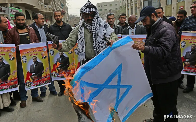 Palestinians burn an Israeli flag during a protest denouncing an assassination of Hamas official, Mazen Faqha who was freed by Israel in a 2011 prisoner swap after he was shot dead by unknown gunmen, in front of Red cros...