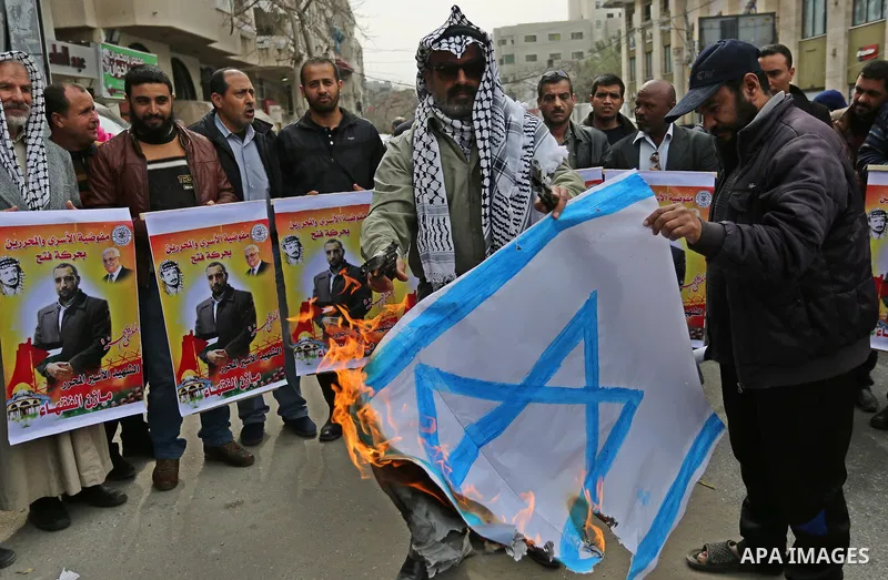 Palestinians burn an Israeli flag during a protest denouncing an assassination of Hamas official, Mazen Faqha who was freed by Israel in a 2011 prisoner swap after he was shot dead by unknown gunmen, in front of Red cros...