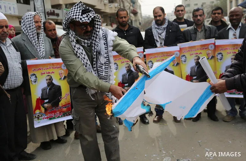 Palestinians burn an Israeli flag during a protest denouncing an assassination of Hamas official, Mazen Faqha who was freed by Israel in a 2011 prisoner swap after he was shot dead by unknown gunmen, in front of Red cros...
