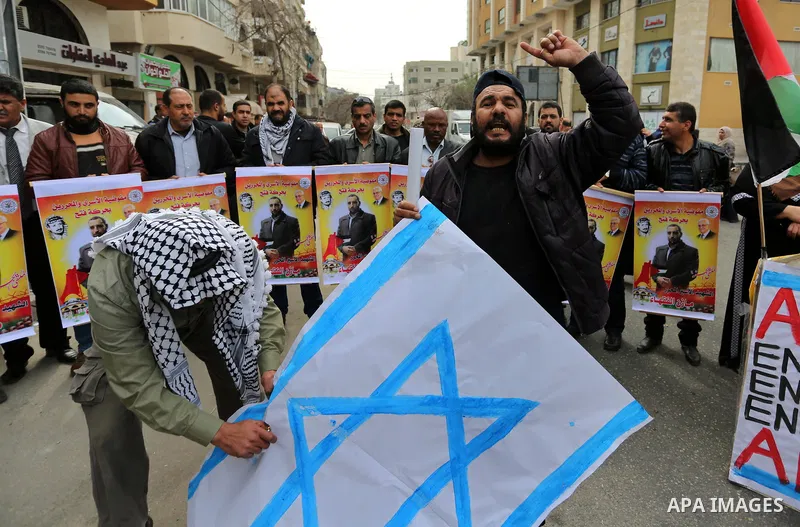 Palestinians burn an Israeli flag during a protest denouncing an assassination of Hamas official, Mazen Faqha who was freed by Israel in a 2011 prisoner swap after he was shot dead by unknown gunmen, in front of Red cros...