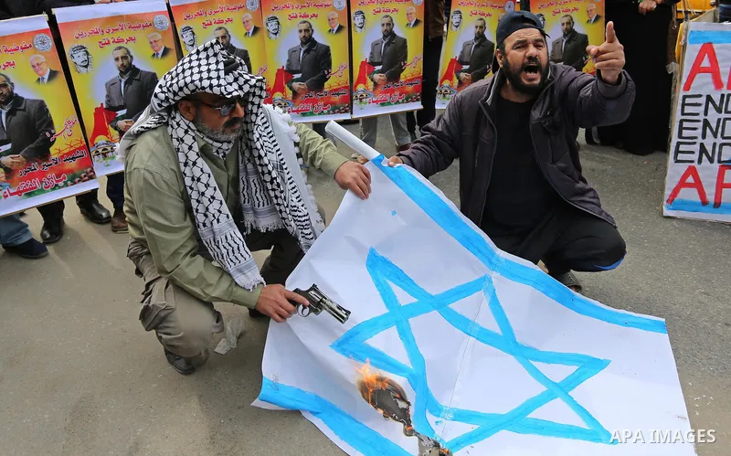 Palestinians burn an Israeli flag during a protest denouncing an assassination of Hamas official, Mazen Faqha who was freed by Israel in a 2011 prisoner swap after he was shot dead by unknown gunmen, in front of Red cros...