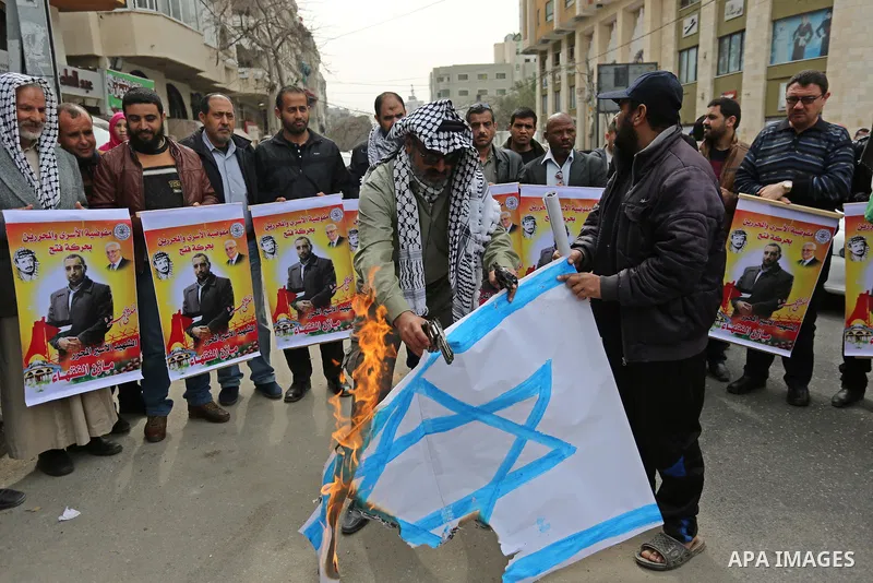 Palestinians burn an Israeli flag during a protest denouncing an assassination of Hamas official, Mazen Faqha who was freed by Israel in a 2011 prisoner swap after he was shot dead by unknown gunmen, in front of Red cros...