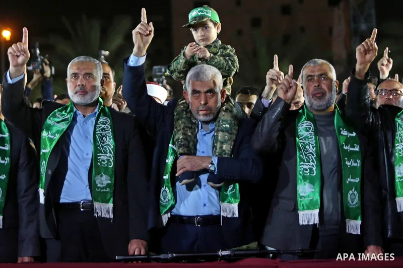 The son of Hamas official, Mazen Faqha, who was shot dead by unknown gunmen sits on the shoulders of Yahya Sinwar, the new leader of Hamas in the Gaza Strip during a memorial service in Gaza city on March 27, 2017. Photo...