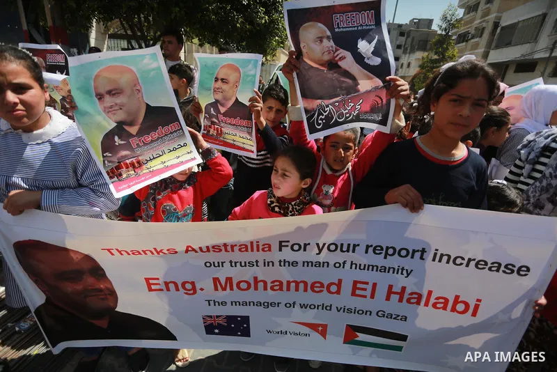 Palestinians hold posters of Mohammad El Halabi, World Vision's manager of operations in Gaza who was accused by Israel of funnelling millions of dollars in aid money to Hamas, during a protest in solidarity with El Hala...