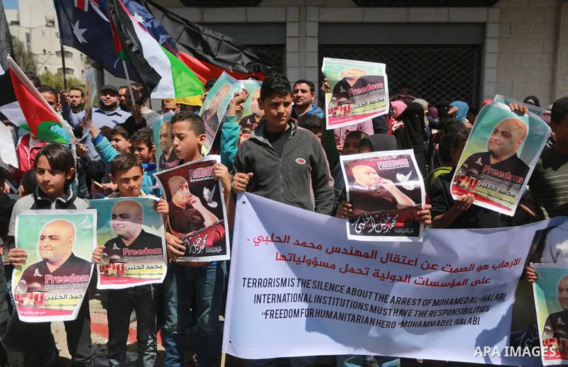 Palestinians hold posters of Mohammad El Halabi, World Vision's manager of operations in Gaza who was accused by Israel of funnelling millions of dollars in aid money to Hamas, during a protest in solidarity with El Hala...