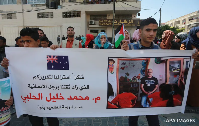 Palestinians hold posters of Mohammad El Halabi, World Vision's manager of operations in Gaza who was accused by Israel of funnelling millions of dollars in aid money to Hamas, during a protest in solidarity with El Hala...
