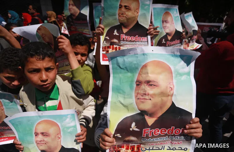 Palestinians hold posters of Mohammad El Halabi, World Vision's manager of operations in Gaza who was accused by Israel of funnelling millions of dollars in aid money to Hamas, during a protest in solidarity with El Hala...