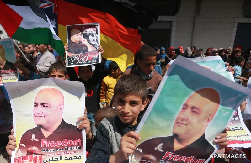 Palestinians hold posters of Mohammad El Halabi, World Vision's manager of operations in Gaza who was accused by Israel of funnelling millions of dollars in aid money to Hamas, during a protest in solidarity with El Hala...