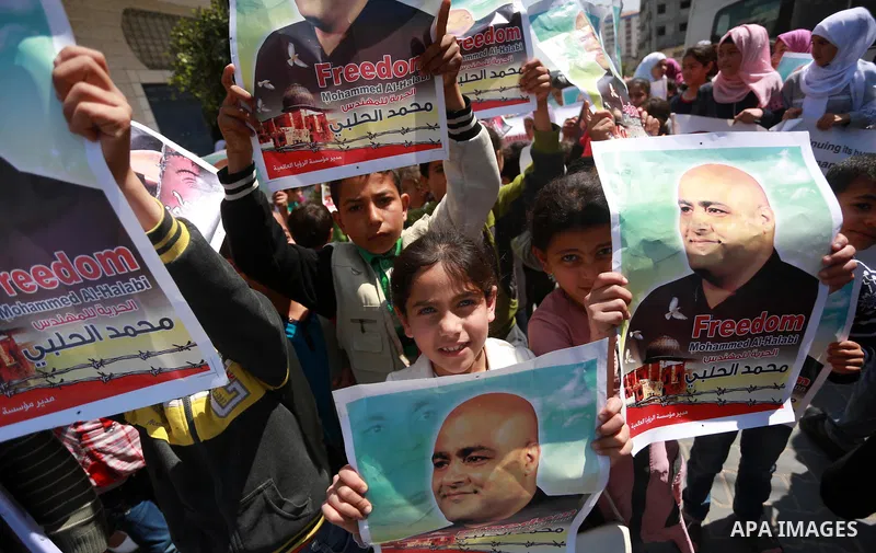 Palestinians hold posters of Mohammad El Halabi, World Vision's manager of operations in Gaza who was accused by Israel of funnelling millions of dollars in aid money to Hamas, during a protest in solidarity with El Hala...