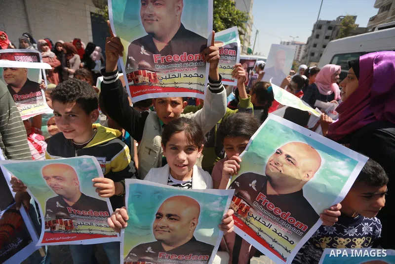 Palestinians hold posters of Mohammad El Halabi, World Vision's manager of operations in Gaza who was accused by Israel of funnelling millions of dollars in aid money to Hamas, during a protest in solidarity with El Hala...