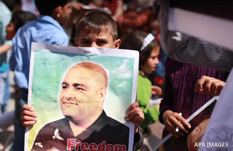 Palestinians hold posters of Mohammad El Halabi, World Vision's manager of operations in Gaza who was accused by Israel of funnelling millions of dollars in aid money to Hamas, during a protest in solidarity with El Hala...