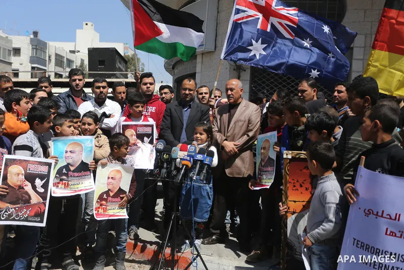 Palestinians hold posters of Mohammad El Halabi, World Vision's manager of operations in Gaza who was accused by Israel of funnelling millions of dollars in aid money to Hamas, during a protest in solidarity with El Hala...