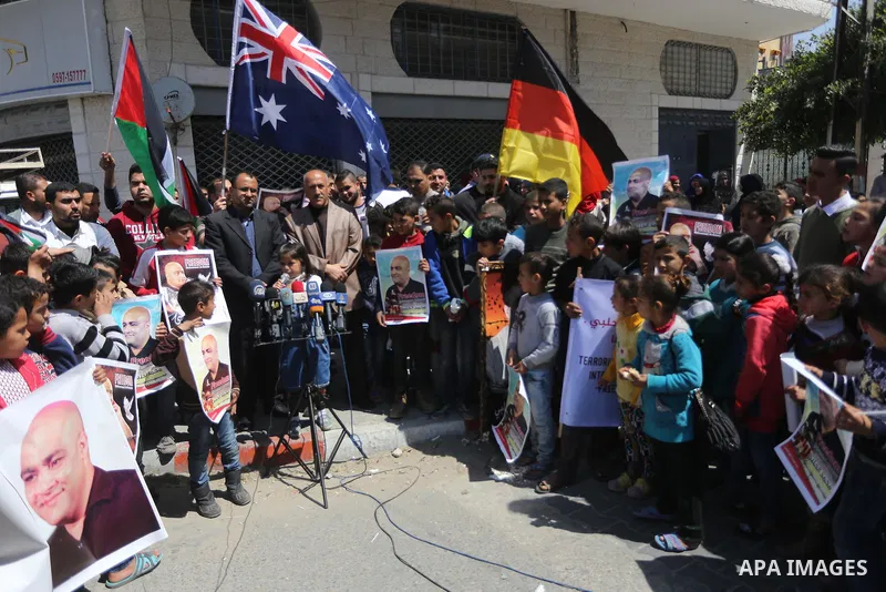 Palestinians hold posters of Mohammad El Halabi, World Vision's manager of operations in Gaza who was accused by Israel of funnelling millions of dollars in aid money to Hamas, during a protest in solidarity with El Hala...