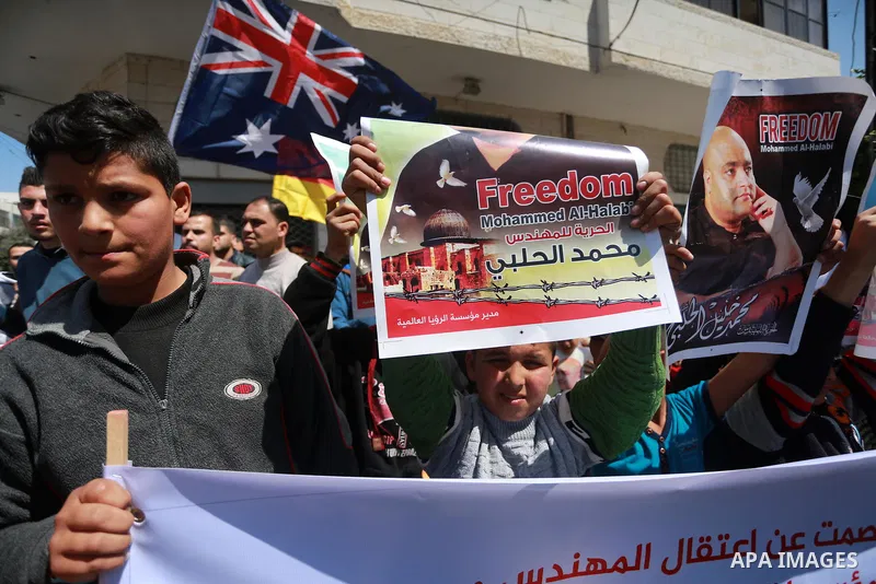 Palestinians hold posters of Mohammad El Halabi, World Vision's manager of operations in Gaza who was accused by Israel of funnelling millions of dollars in aid money to Hamas, during a protest in solidarity with El Hala...