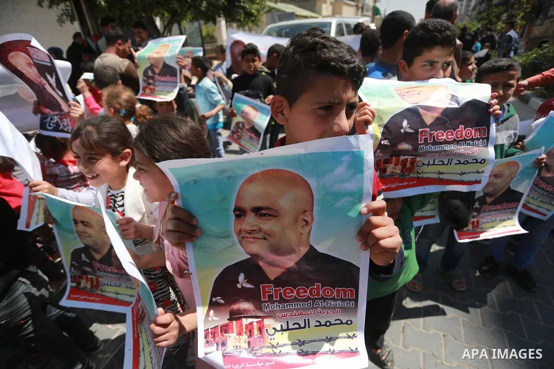 Palestinians hold posters of Mohammad El Halabi, World Vision's manager of operations in Gaza who was accused by Israel of funnelling millions of dollars in aid money to Hamas, during a protest in solidarity with El Hala...