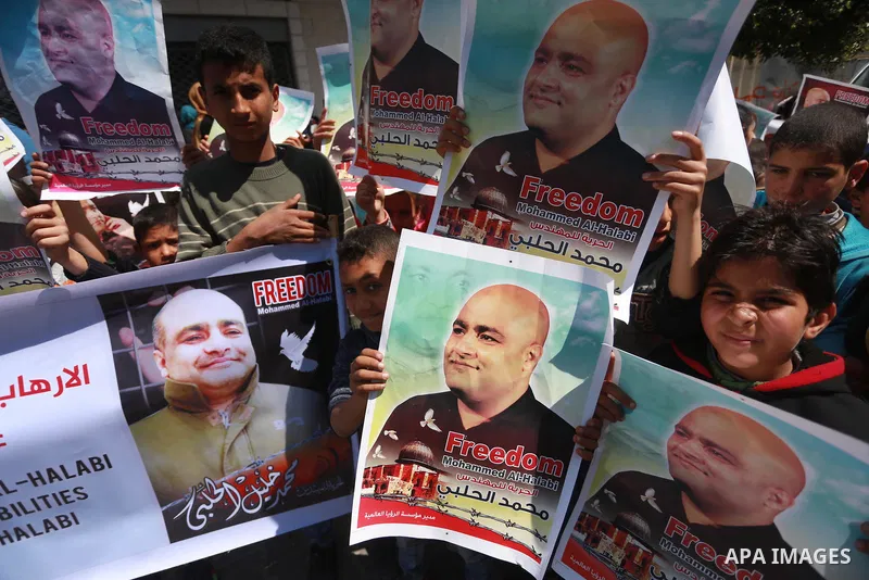Palestinians hold posters of Mohammad El Halabi, World Vision's manager of operations in Gaza who was accused by Israel of funnelling millions of dollars in aid money to Hamas, during a protest in solidarity with El Hala...