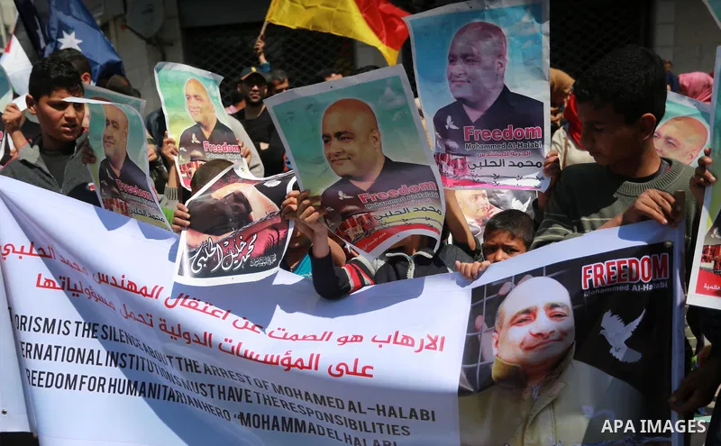 Palestinians hold posters of Mohammad El Halabi, World Vision's manager of operations in Gaza who was accused by Israel of funnelling millions of dollars in aid money to Hamas, during a protest in solidarity with El Hala...