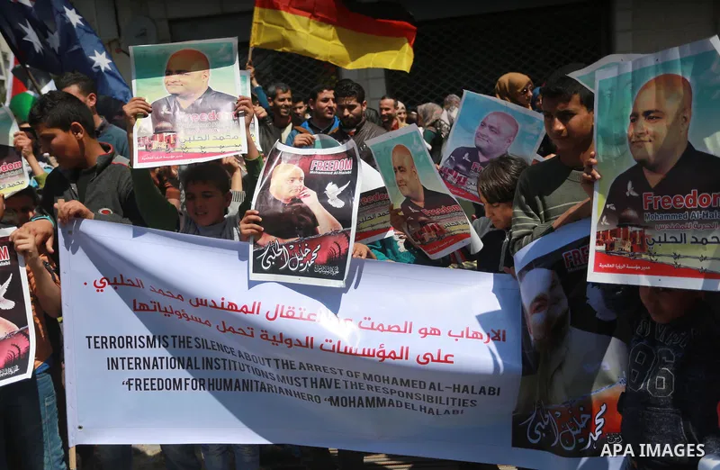 Palestinians hold posters of Mohammad El Halabi, World Vision's manager of operations in Gaza who was accused by Israel of funnelling millions of dollars in aid money to Hamas, during a protest in solidarity with El Hala...