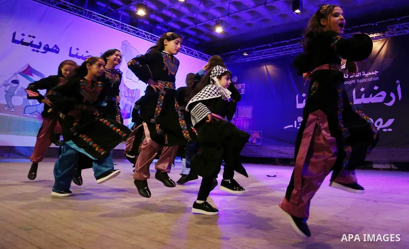 Palestinian children perform a traditional dance during a festival titled "our land..our identity" marking the Land day in Gaza city on March 29, 2017. Photo by Ashraf Amra