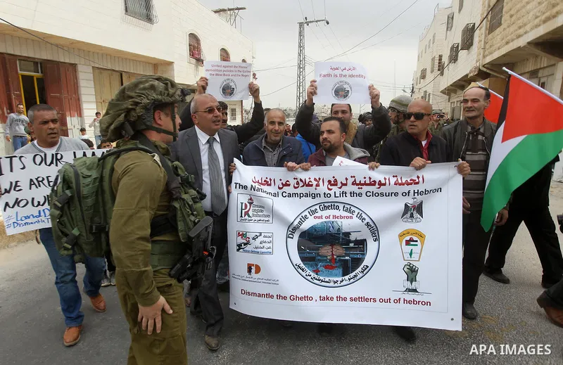 Palestinian demonstrators hold banners during a protest marking Land Day in the West Bank city of Hebron March 30, 2017. Photo by Wisam Hashlamoun