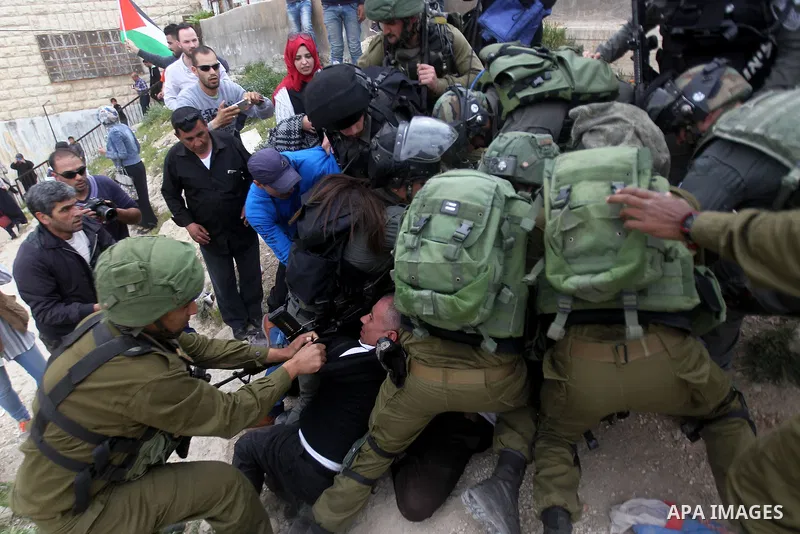 Israeli troops detain a Palestinian demonstrator during a protest marking Land Day in the West Bank city of Hebron March 30, 2017. Photo by Wisam Hashlamoun