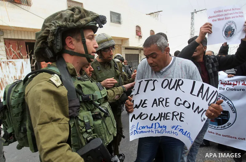 Palestinian demonstrators hold banners during a protest marking Land Day in the West Bank city of Hebron March 30, 2017. Photo by Wisam Hashlamoun