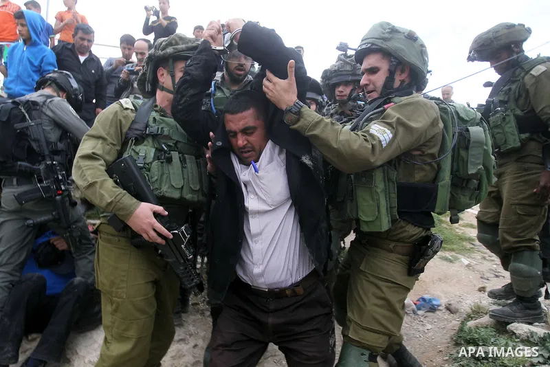 Israeli troops detain a Palestinian demonstrator during a protest marking Land Day in the West Bank city of Hebron March 30, 2017. Photo by Wisam Hashlamoun