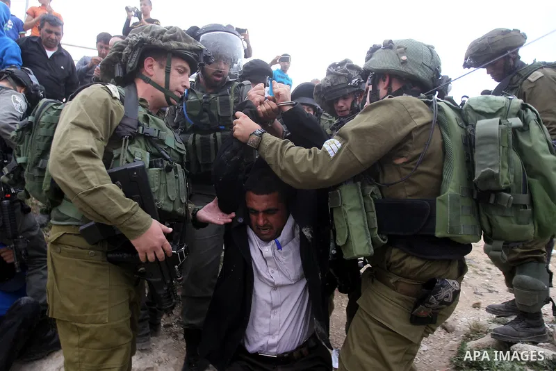 Israeli troops detain a Palestinian demonstrator during a protest marking Land Day in the West Bank city of Hebron March 30, 2017. Photo by Wisam Hashlamoun
